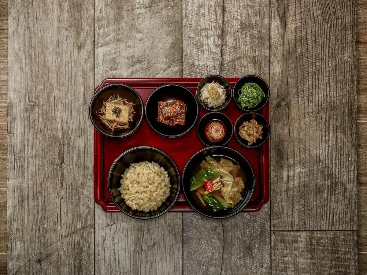 Korean temple food: eine Schale Reis, Tofu, Kimchi und verschiedene Gemüsebeilagen auf einem roten Tablett.