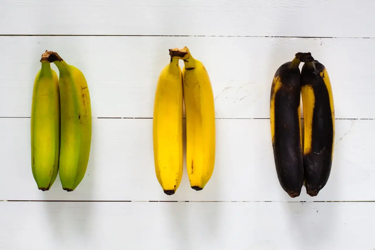 Drei Paare Bananen: links unreif grün, in der Mitte reif gelb, rechts überreif schwarz.