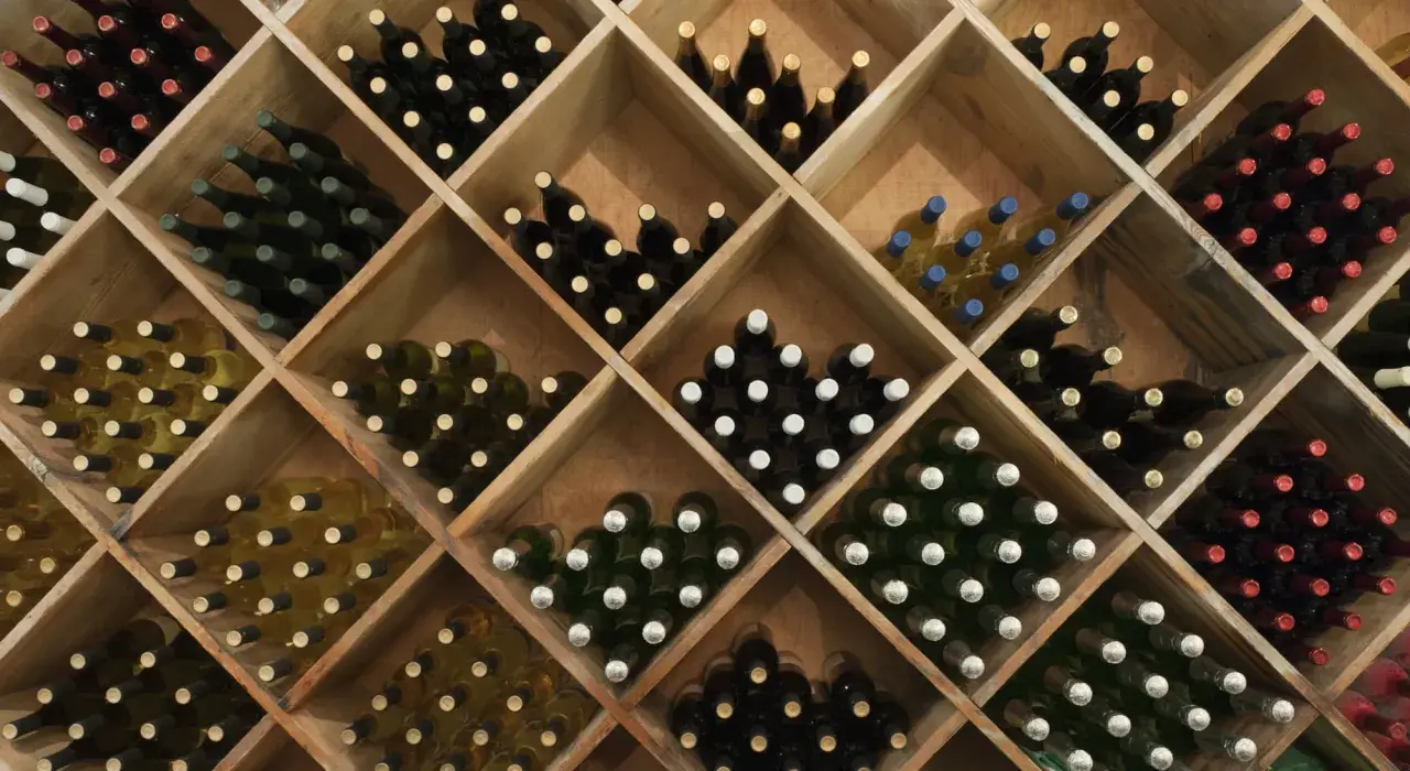 Weinregal mit vielen Flaschen Rotwein und Weißwein. Die Frage, wie lange kann man Rotwein lagern, wird hier durch die Vielfalt der Flaschen angedeutet.