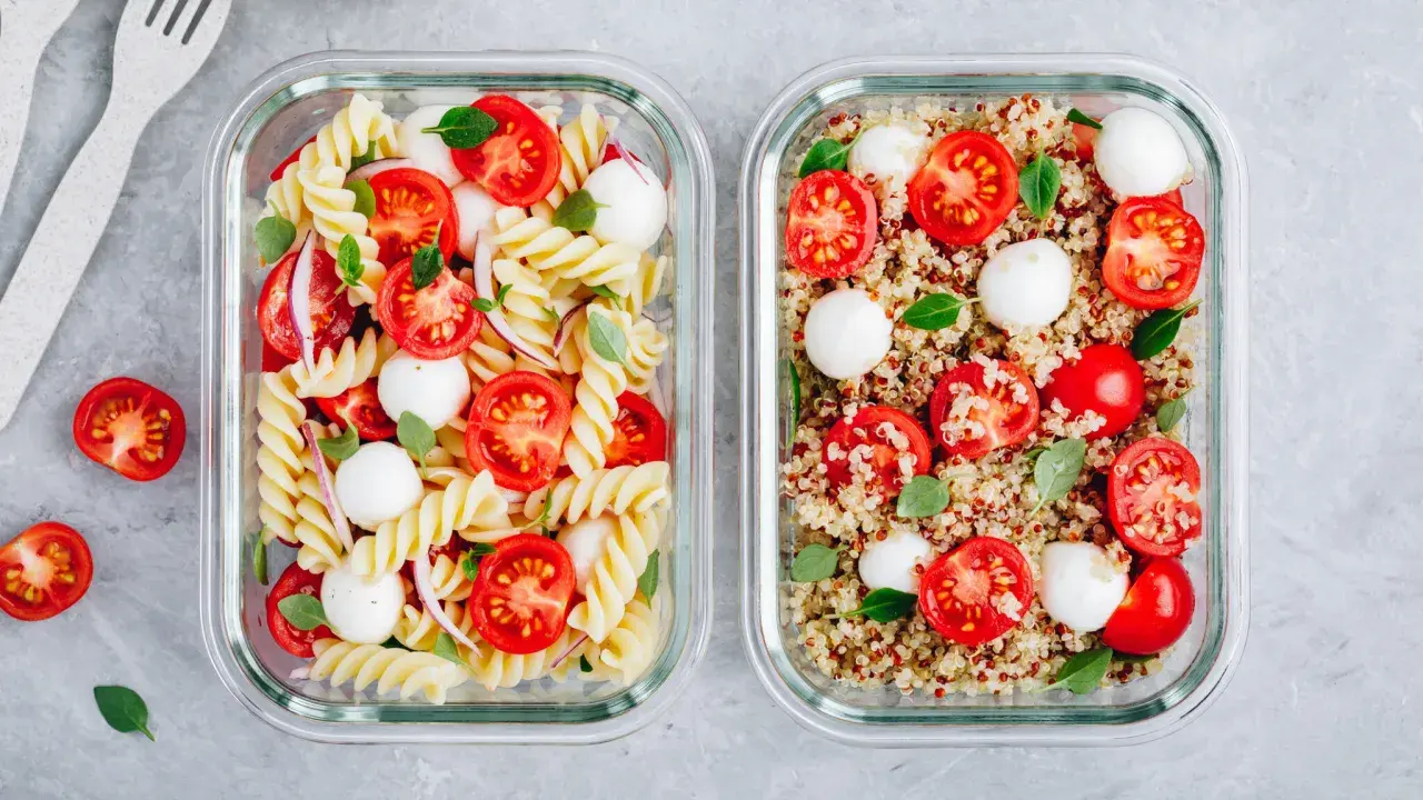 Zwei Behälter für meal prep vegetarisch: Nudelsalat mit Tomaten und Mozzarella und Quinoasalat mit Tomaten und Mozzarella.