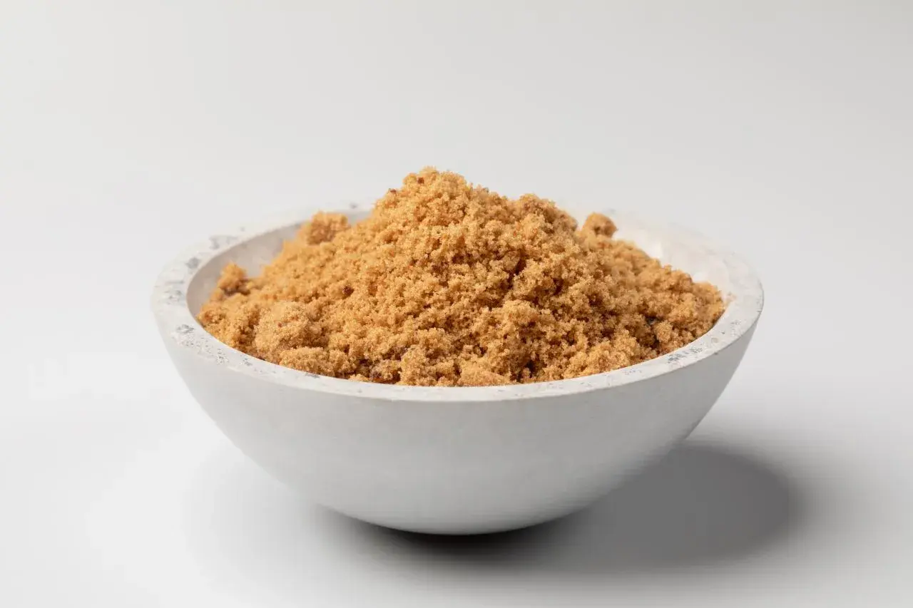 Schüssel mit dunklem Muscovado-Zucker, dessen feine Körner eine warme, karamellige Farbe haben.