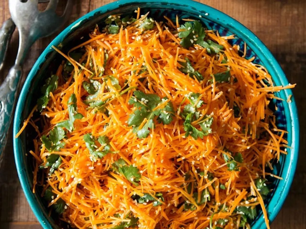 Ein erfrischender eiskraut salat aus geraspelten Karotten, garniert mit Koriander und Sesam.