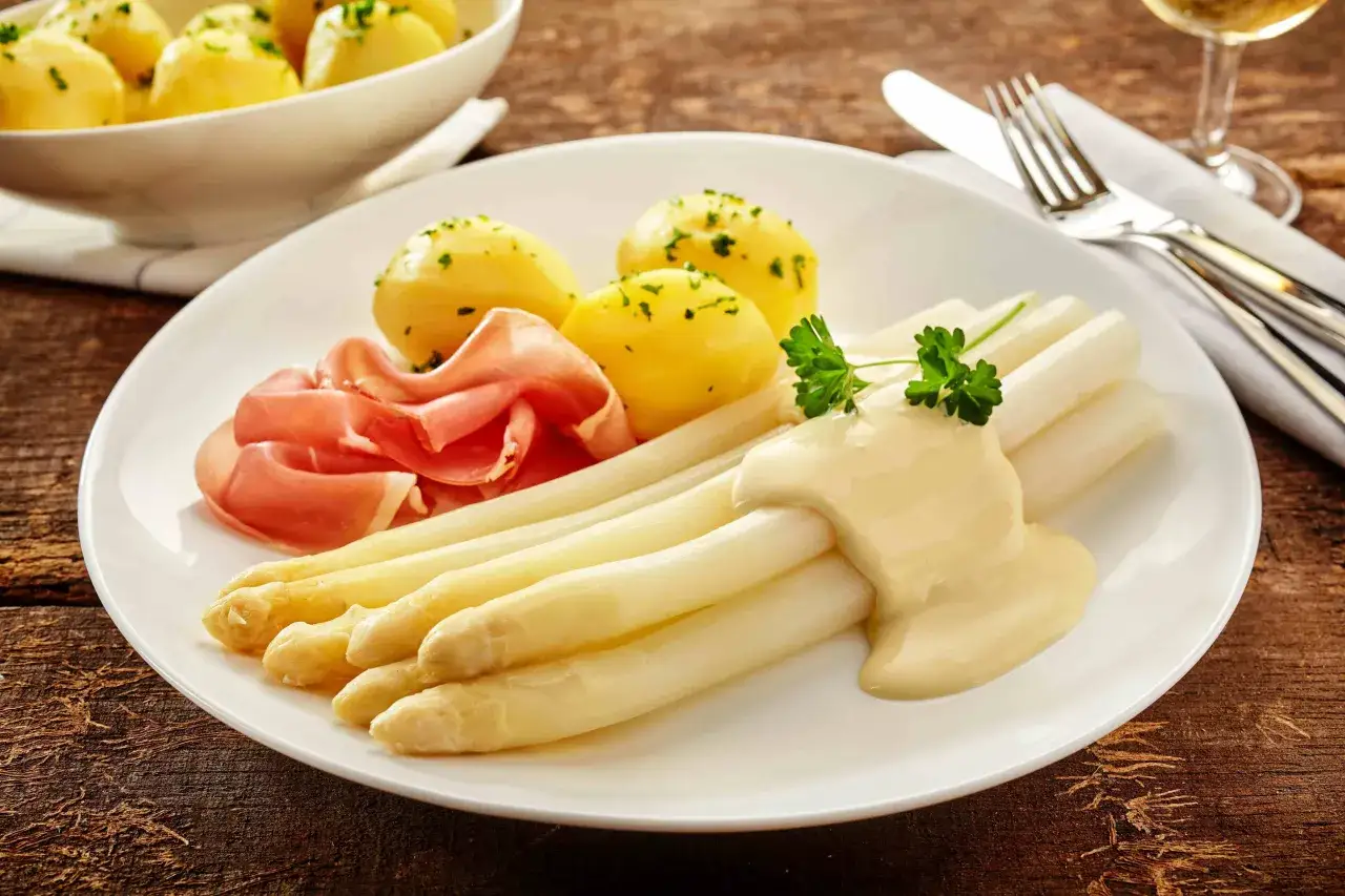 Frischer weißer Spargel aus dem Glas mit cremiger Sauce Hollandaise, dazu Pellkartoffeln und Schinken.