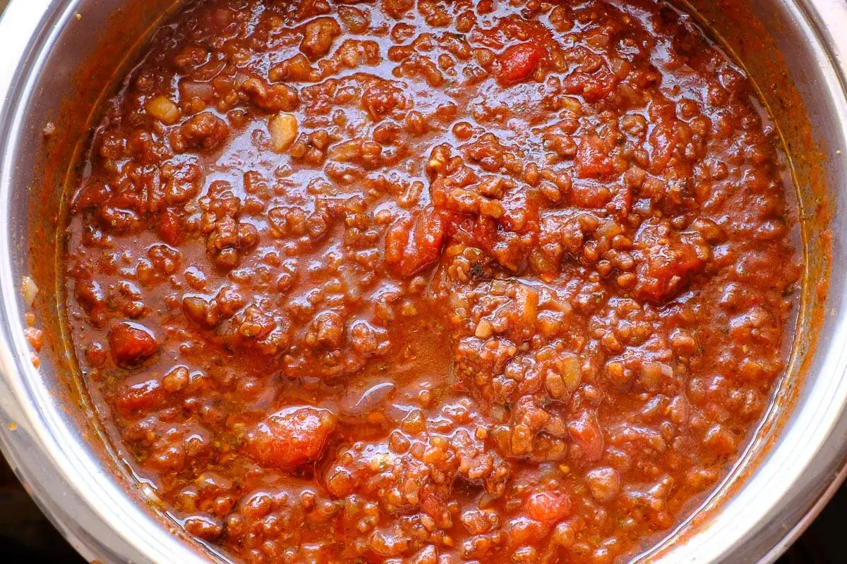 Herzhafte rotwein bolognese Sauce in einem Topf, mit Hackfleisch und Tomatenst&uuml;cken.
