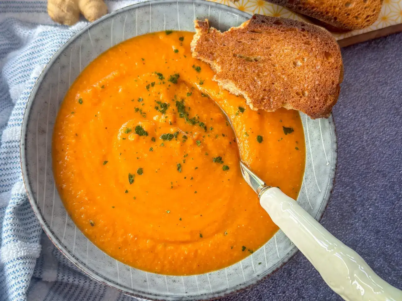 Cremige rote Linsensuppe mit Kokosmilch, garniert mit Petersilie und serviert mit ger&ouml;stetem Brot. Ein k&ouml;stliches Rezept f&uuml;r kalte Tage.