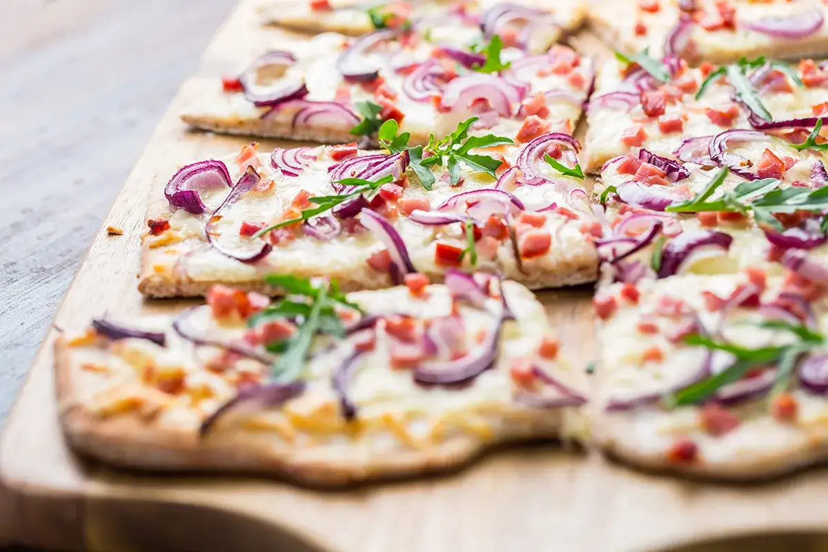 Flammkuchen mit roten Zwiebeln und Speck, frisch aus dem Ofen. So einfach ist es, Flammkuchen zu machen!