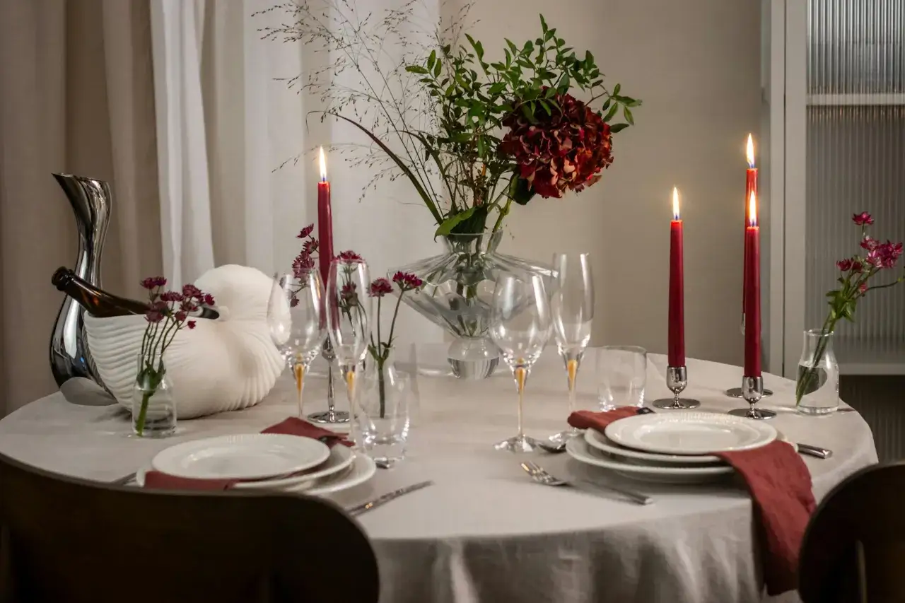 Festlich gedeckter Tisch mit Kerzen, Blumen und Gl&auml;sern, bereit f&uuml;r einen Wein Aperitif.