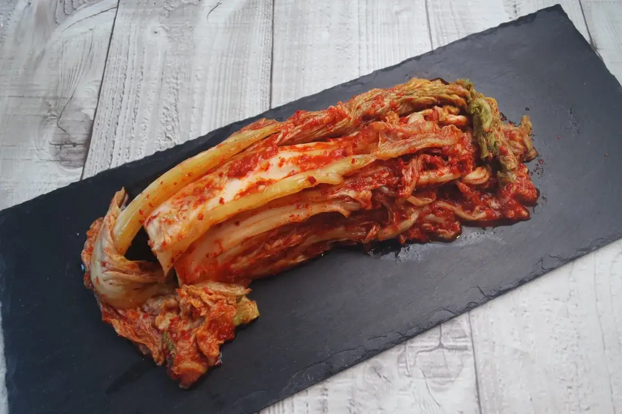 Ein halber Kopf fermentierter scharfer Kohl, eine beliebte koreanische Vorspeise, liegt auf einem schwarzen Stein.