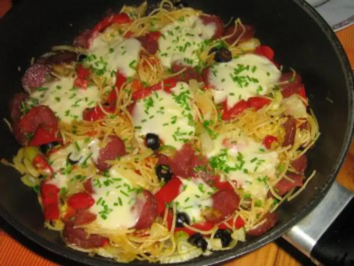 Spaghetti mit Salami, Paprika, Oliven und geschmolzenem Käse, bestreut mit Schnittlauch. Ein herzhaftes Gericht, das an Fenchel erinnert.