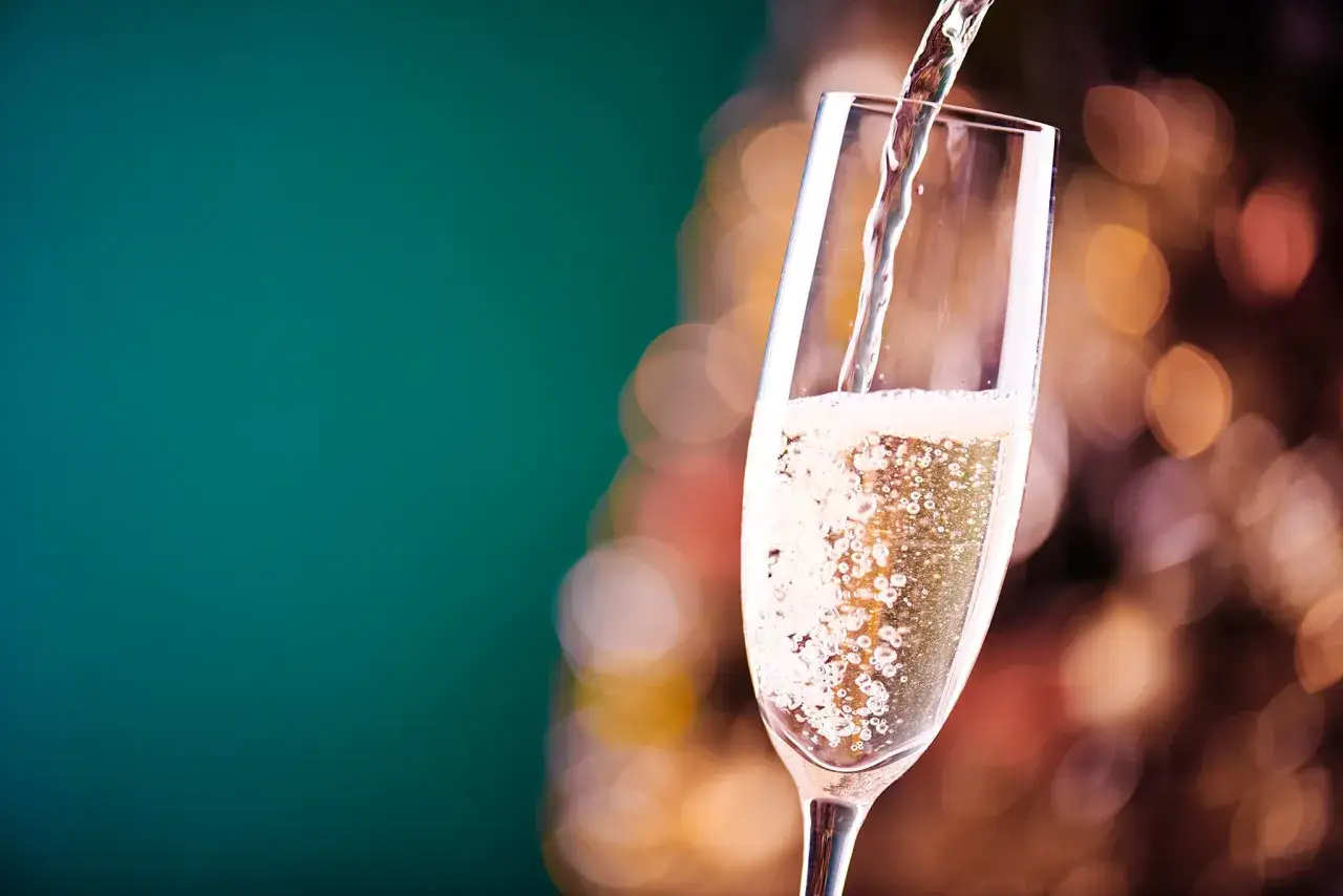 Sekt wird in ein Glas gegossen, sprudelnd und festlich. Ein guter Grund, sich zu fragen, was ist der Unterschied zwischen Sekt und Champagner.