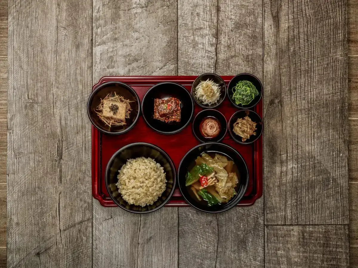 Korean temple food: eine Schale Reis, Tofu, Kimchi und verschiedene Gemüsebeilagen auf einem roten Tablett.