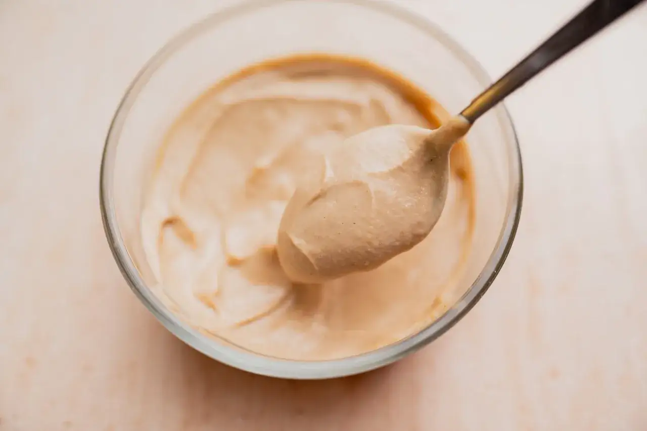 Cremige Tahini-Sauce auf einem L&ouml;ffel, bereit zum Verfeinern von Gerichten. Was ist Tahini-Sauce? Sesamcreme!