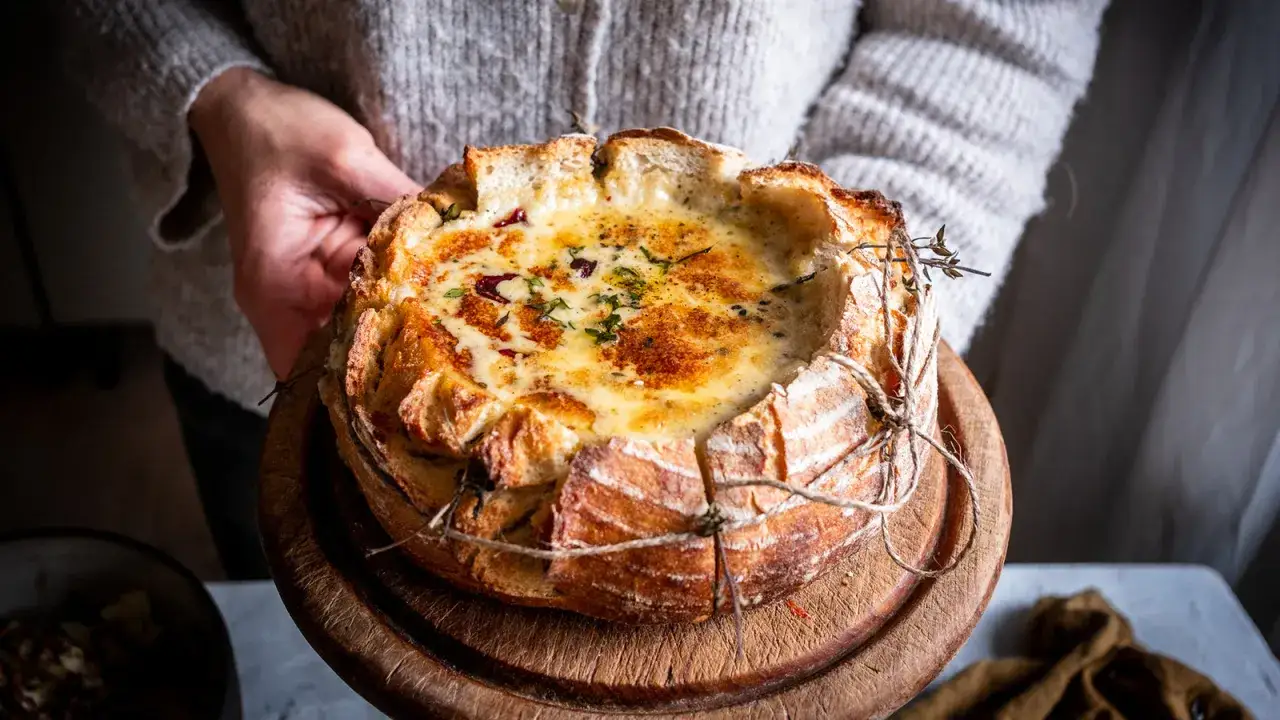Ein Brotlaib, gef&uuml;llt mit cremigem, geschmolzenem K&auml;se, bereit f&uuml;r ein gem&uuml;tliches Schweizer Fondue.