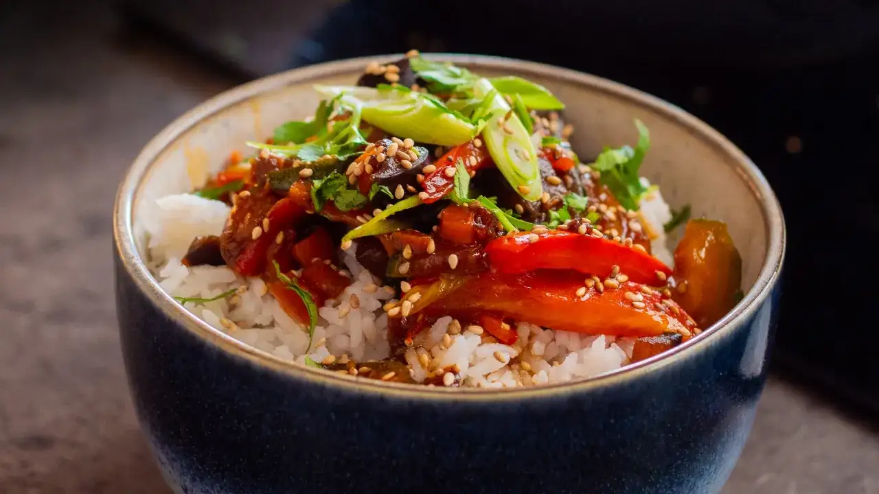 Reisschüssel mit gebratenem Gemüse und einer köstlichen teriyaki sauce, garniert mit Frühlingszwiebeln und Sesam.