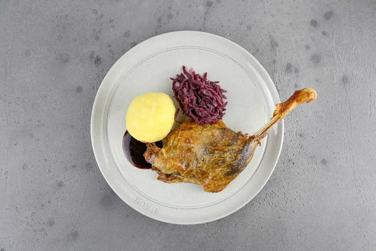 Knusprige G&auml;nsekeule mit Kl&ouml;&szlig;en und Rotkohl. Ein Klassiker, zu dem ein kr&auml;ftiger Rotwein passt. Welcher Wein zu Gans?